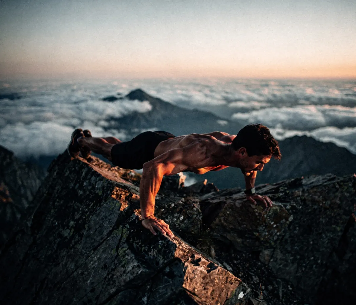Man doing push-ups on a mountain ridge at dawn